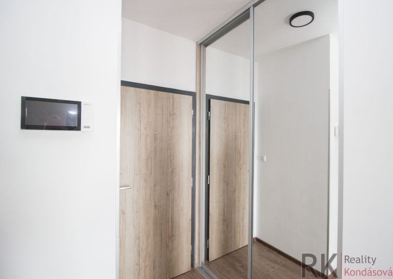 Interior of a 1-room apartment with a wooden decor floor and a built-in wardrobe.