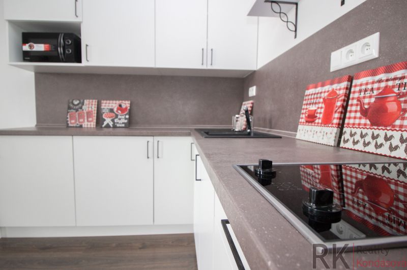 White kitchen with a countertop in a studio apartment, floor with wood decor.
