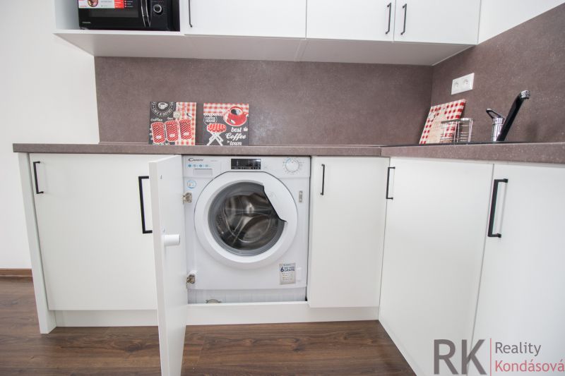 Kitchen unit with a washing machine in a studio apartment, floor with wooden decor.