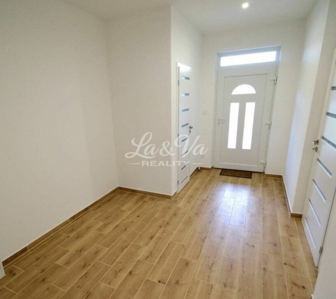 In the family house, there is a bright hallway with a wooden decor floor and light-colored doors.