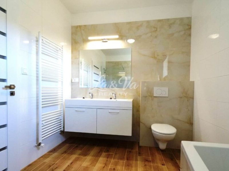 A bathroom in a family house with a wooden decor floor, double sink, and a shower.