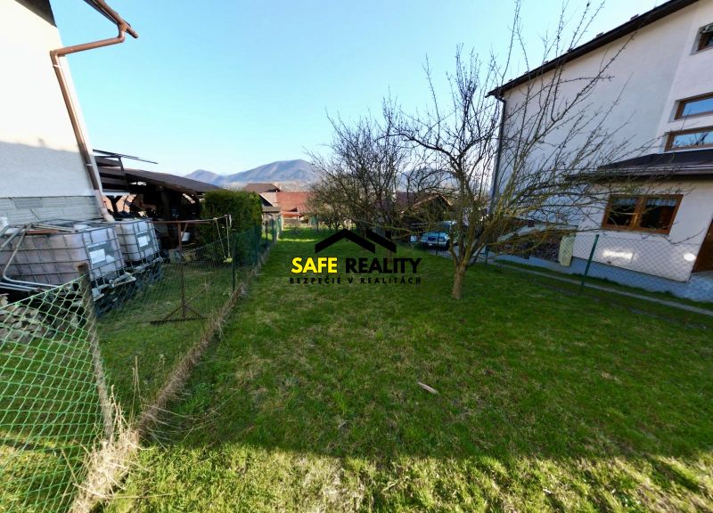 Gardens in Kysucké Nové Mesto with lawns, trees, houses, and a view of the mountains.