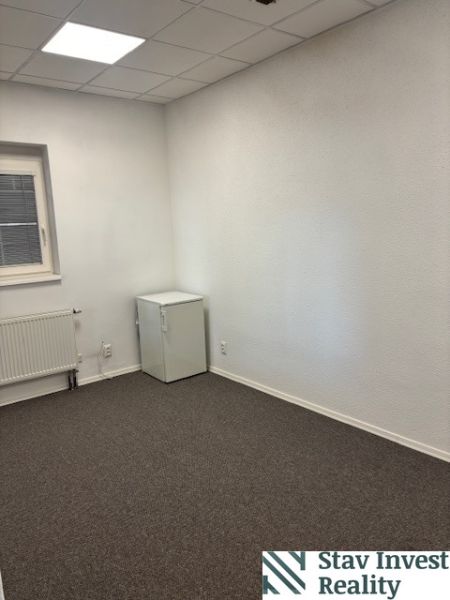 Offices with a window, radiator, and white wall, carpet.