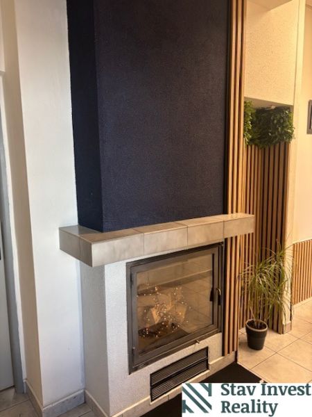 Office interior with a fireplace, flowers, and wooden wall paneling.
