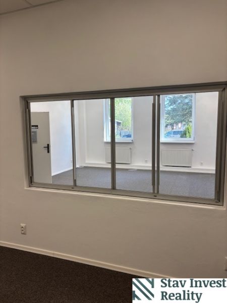 Offices with a large window, white walls, and radiators.