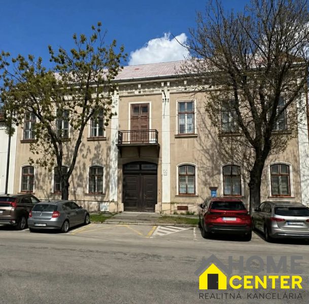 A building in Komárno used for special properties, surrounded by trees and a parking lot.