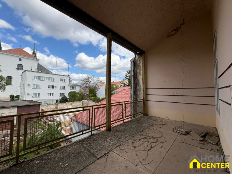 Unusual properties in Komárno with a damaged wall and a view of the city architecture.