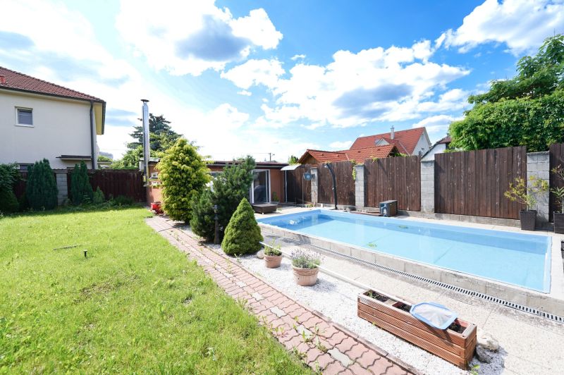 The family house on Kladnianska Street in Bratislava-Ružinov has a swimming pool, a lawn, and a fenced yard.