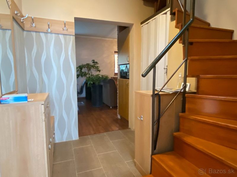 A hallway in a family house with a staircase, a patterned wall, and a floor with a wooden decor.