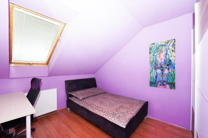 Purple wall, bed, painting, skylight, and desk in a family house.