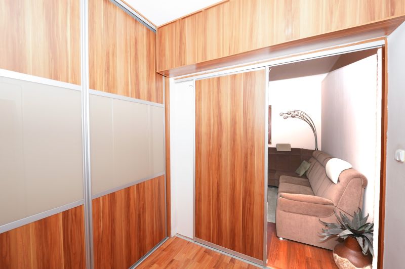 Built-in wardrobe with sliding doors and a wooden decor floor in a family house.