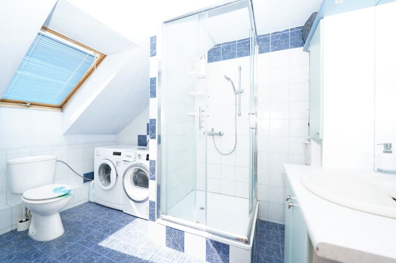 Bathroom in a family house with tiled floor, shower corner, and washing machine.