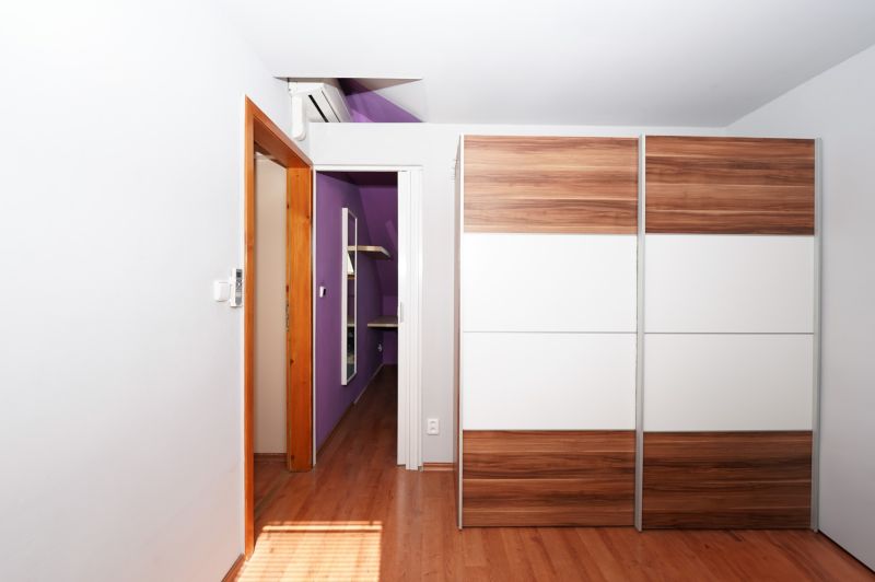 Wardrobe with sliding doors, floor with wood decor, purple wall, air conditioning.