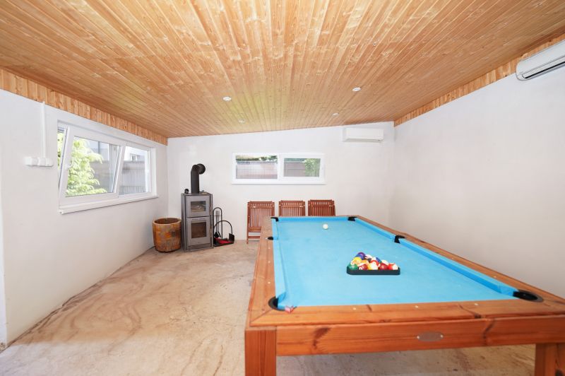 Game room in a family house with a pool table and a wood-burning fireplace.
