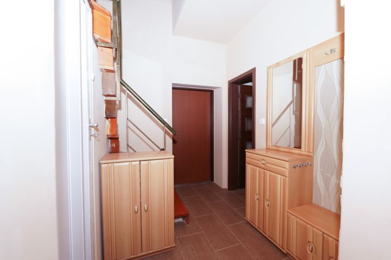A hallway in a family house with shelves, a mirror, and stairs, with a wooden decor floor.