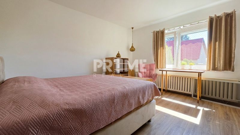 A bedroom in a family house with a bed, a chair, and a wooden decor floor.