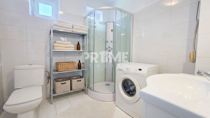 Bathroom of a family house with a shower, washing machine, and a towel rack.