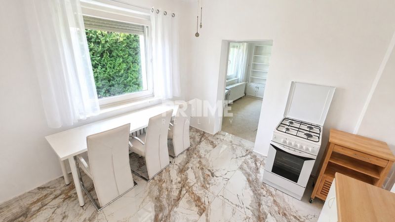 Dining room with a white table, stove, and stone floor in a family house.