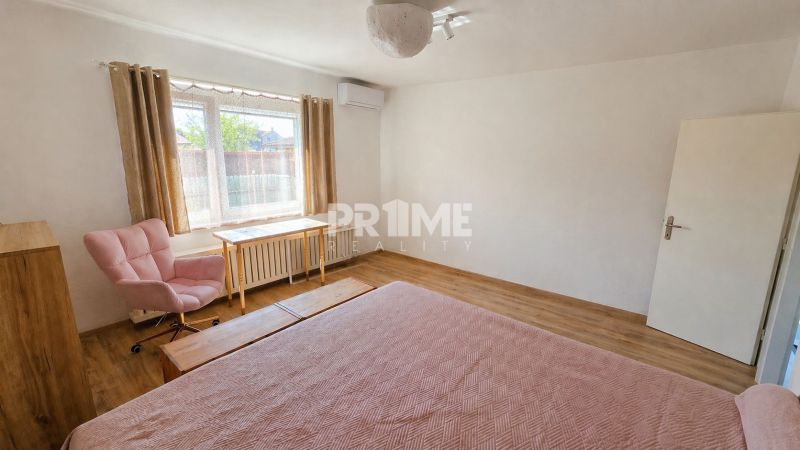 A bedroom in a family house with a wooden decor floor and light furnishings.
