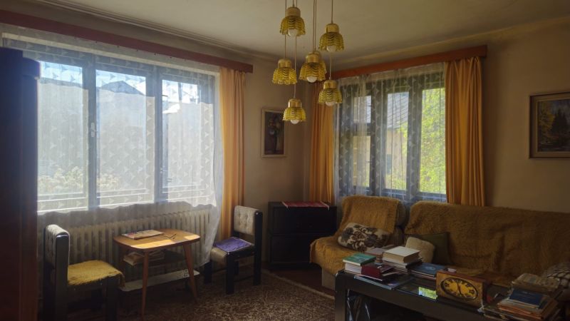 Living room in a family house with retro chandeliers and large windows with curtains.