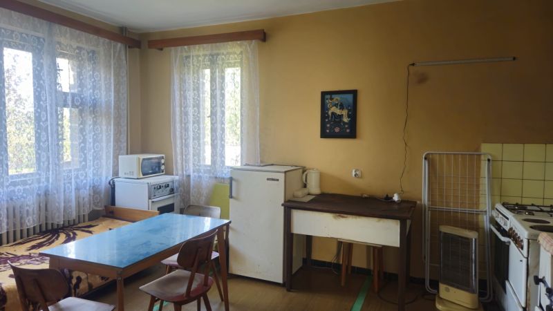 A kitchen in a family house with simple furniture, a table, and appliances.