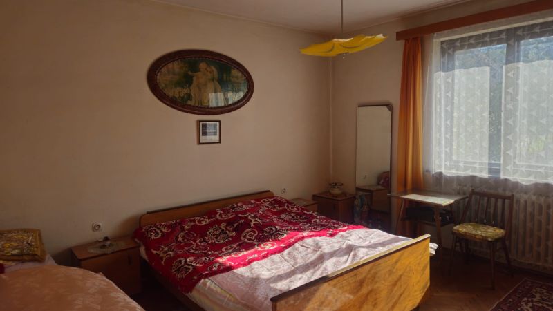 Bedroom in a family house with a bed, nightstands, a window, and a mirror.