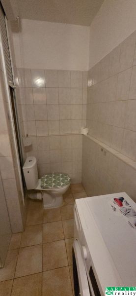 A bathroom in a studio apartment with tiles and a washing machine.