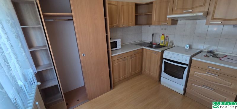 A kitchen in a one-room apartment with a kitchen unit and a floor with a wooden decor.