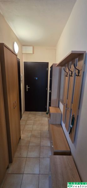 A narrow entrance area with tiles and wooden furniture in a studio apartment.