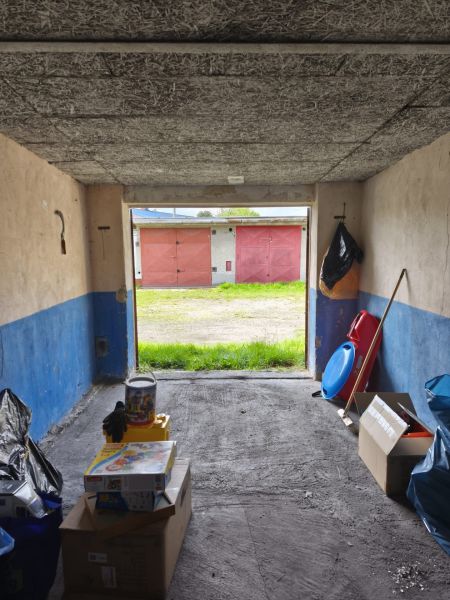 In the garage, there are stored boxes and toys, the background shows garages on Dlhá Street in Prievidza.