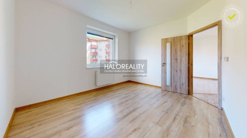 A studio apartment with a wooden floor, white walls, and a window to the exterior.