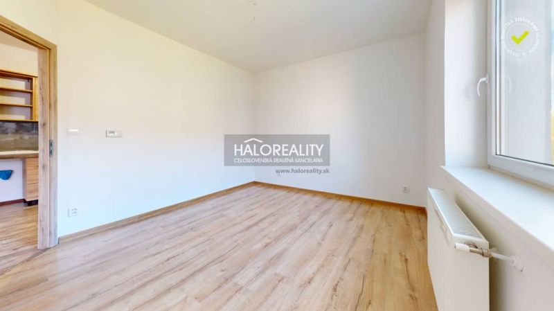 A studio apartment with white walls and a wood-patterned floor.