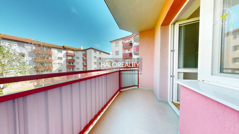 A balcony in a studio apartment, view of apartment buildings in Lučenec on a sunny day.