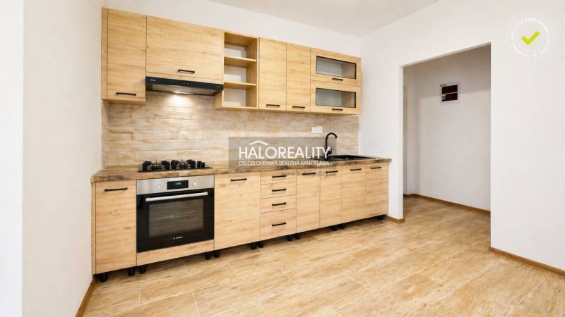 A kitchenette in a studio apartment with a wood-patterned floor and built-in appliances.