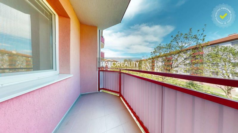 A studio apartment balcony with a view in the city of Lučenec, with pink walls and railing.