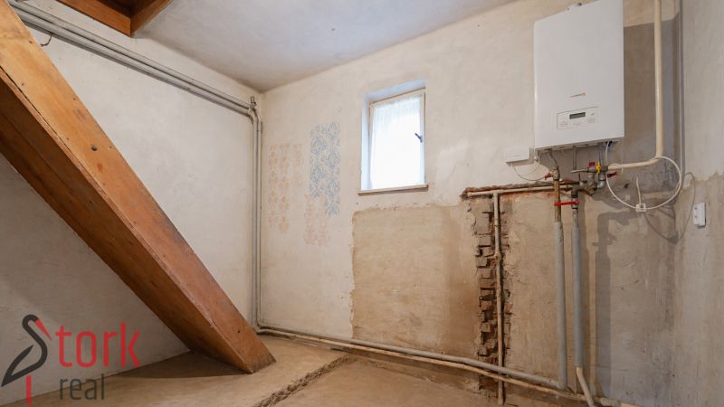 Boiler room with a boiler and piping in a family house, with a small window.