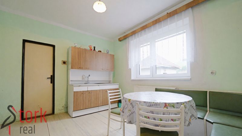 A kitchen in a family house with a dining table, chairs, and a light floor.