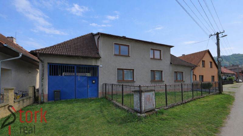 A family house in Horná Súča with a garage and a fenced lawn on a quiet street.