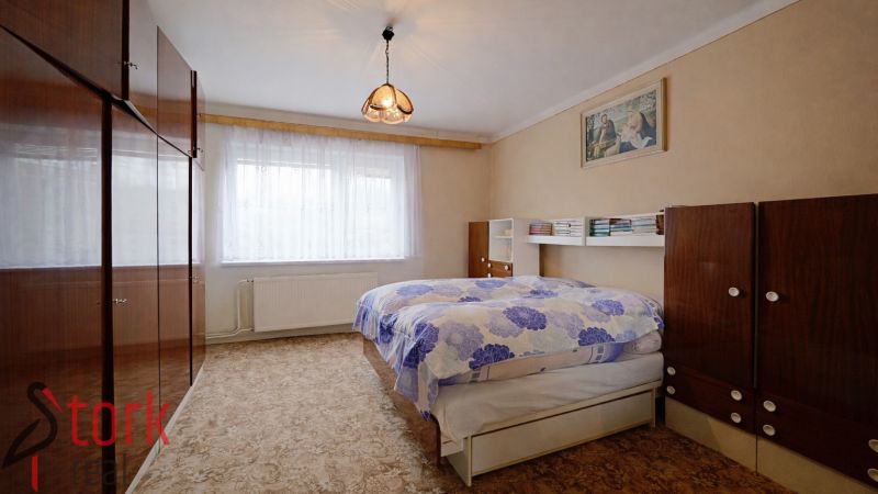 A bedroom in a family house with carpeted flooring and wooden furniture.