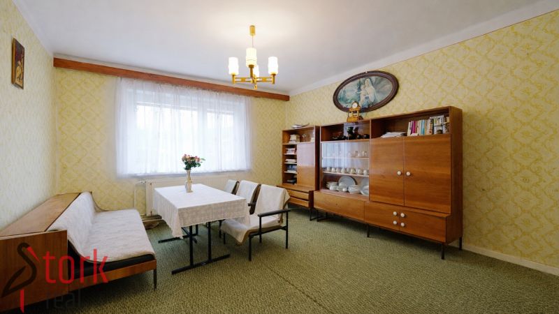 Living room in a family house with retro furniture, colorful walls, and a synthetic carpet.