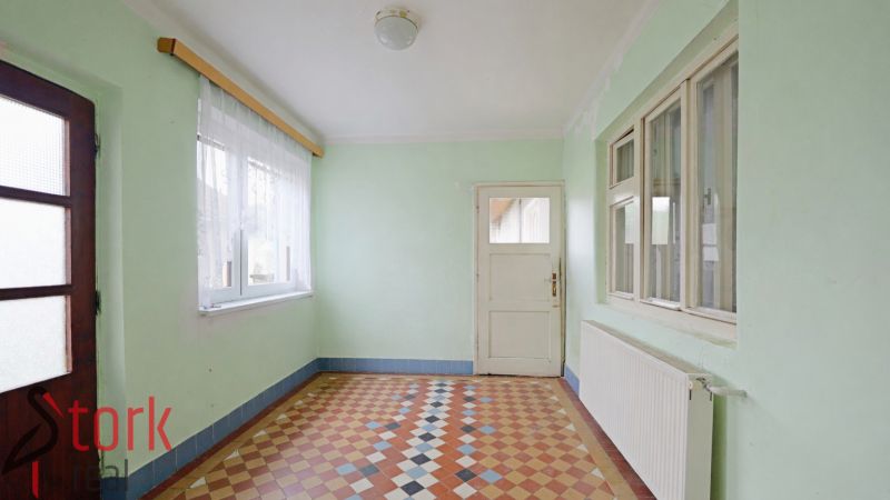 Interior of a family house with tiled floors and pastel walls, with light streaming through the windows.