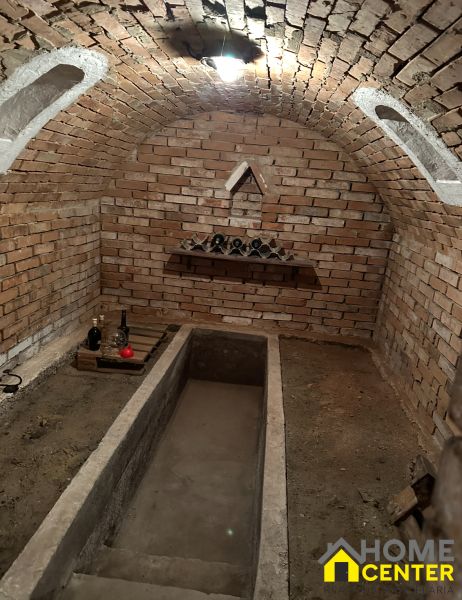 Brick cellar in the Gardens with a wine shelf and a small staircase.
