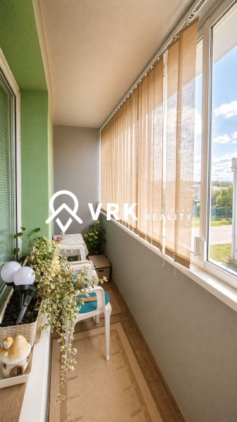 A balcony in a 4-room apartment with flowers and seating, overlooking Turňa nad Bodvou.