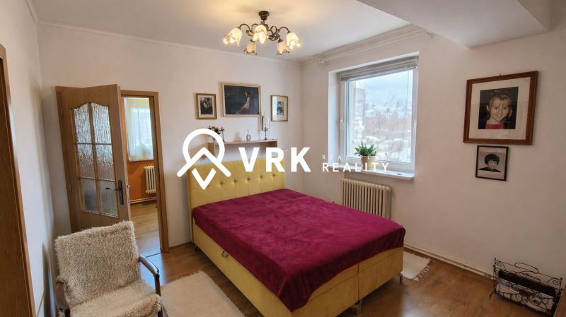 A bedroom in a 4-room apartment with a wooden decor floor and a prominent bed headboard.