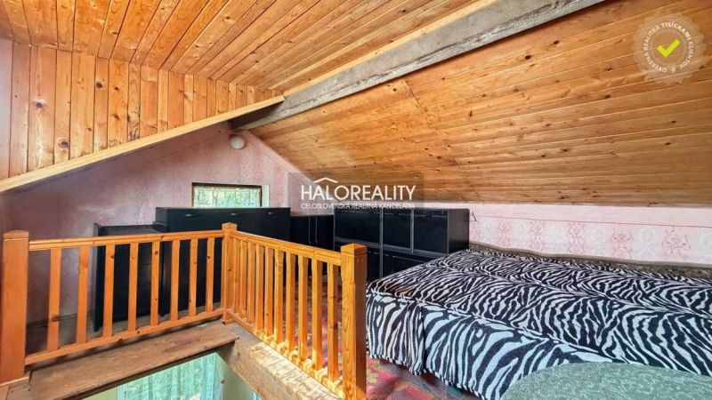 Attic room with wooden decor flooring, a bed, and railing in the attic of the garden.