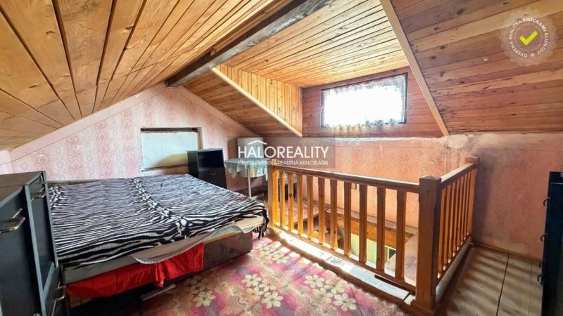 Attic room with wooden decor, bed, and wallpaper, illuminated by a window.