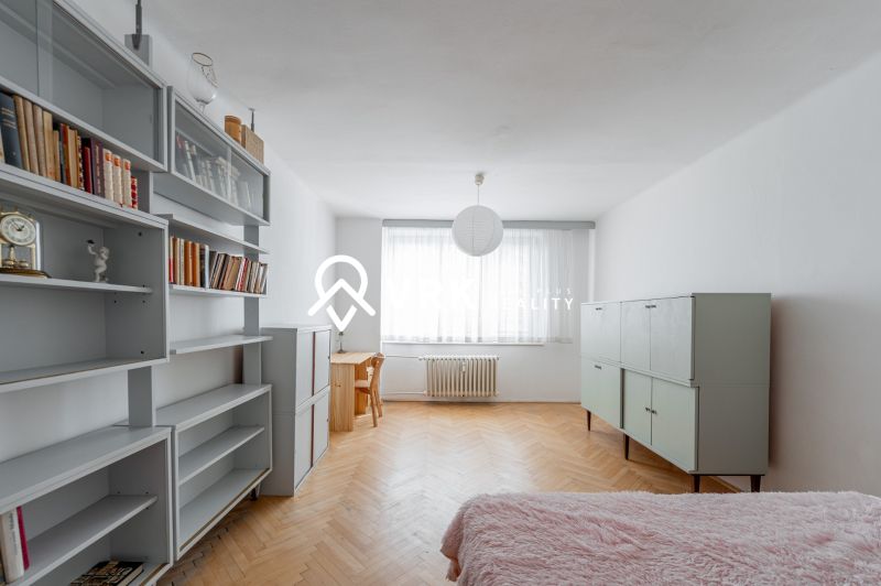 A room with shelves and a bed on the floor with a wooden decor in a 2-room apartment.