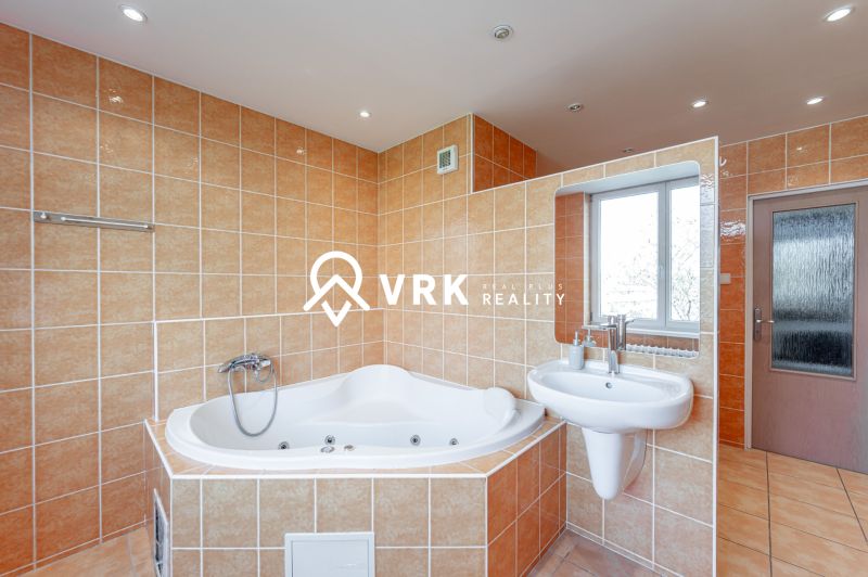 Bathroom in a 2-room apartment with a whirlpool bathtub, sink, and window.
