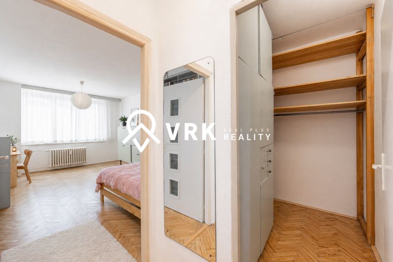 Interior of a 2-room apartment with a wooden decor floor, furniture, and a wardrobe.
