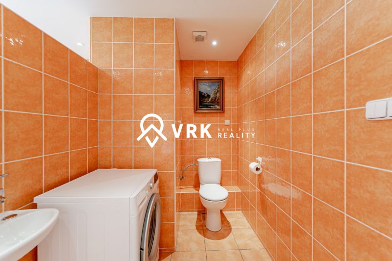 Bathroom with orange tiles, a washing machine, and a toilet in a 2-room apartment.